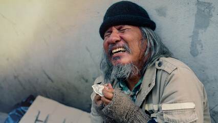 An old Asian man is rejoicing as he receives money from a passerby to help. A homeless man shows off his banknotes and a very happy expression on his face. Homeless not have home