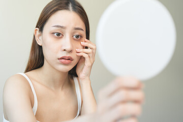 lack of sleep problem,  Worried Asian young woman pointing finger at dark circles under her eyes