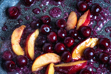 Close-up of delicious, caramelized cherries and nectarines in pan. Appetizing pan-fried fruits for dessert. Excellent image for homemade dessert banners and advertisements.

