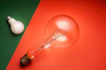 old high consumption electric bulb vs high energy efficiency LED bulb. Energy saving. Flat lay red and green background.