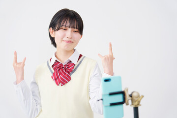 白背景でスマホで動画配信する女子高生