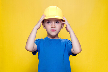 Portrait preschooler in a helmet builder on yellow background