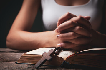 woman praying on book holding cross
