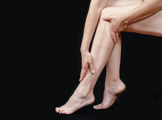 Female bare legs in profile. Slender legs, full thighs. Problems of excess weight in middle-aged women. Black background.
