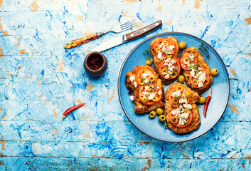 Meat schnitzel with cheese, olives and tomato