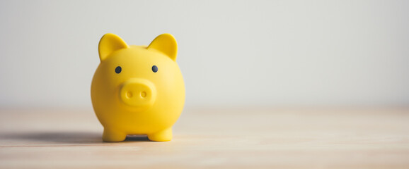 Panoramic yellow piggy bank on wooden table. Concept saving money finance business investment.