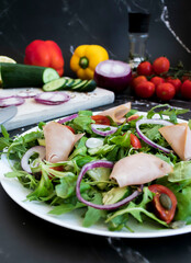 Delicious healthy salad with vegetables and meat. in a white plate on the table.
