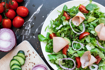 Delicious healthy salad with vegetables and meat. in a white plate on the table.
