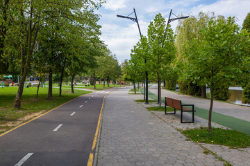 Fototapeta na wymiar Bicycle path, jogging path and pedestrian alley in the city park on the lake on a summer day