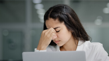 Close-up young sad tired woman manager looking at laptop screen in office feeling exhausted...