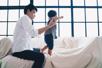 Toddler asian boy first step practice with dad in cozy room