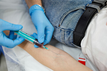 Close-up view of a doctor or laboratory assistant taking blood from a vein of a female patient
