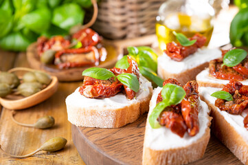 Bruschetta with sun-dried tomatoes, cheese, basil and capers. Traditional appetizer for aperitivo in Italy. High quality photo. Copy space