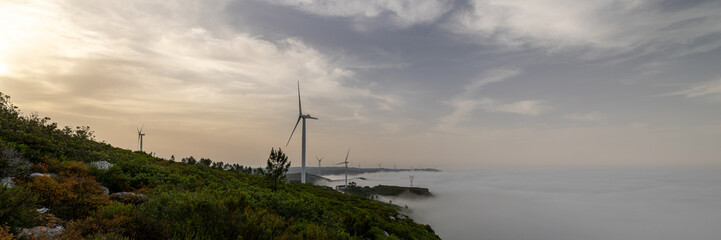 Fototapeta na wymiar Wind turbines with mountain and fog