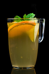 Apple orange tea with spices and mint with pieces orange and mint on a black background