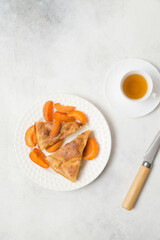 Homemade peach pie with cup of green tea and knife on white background. Top view.