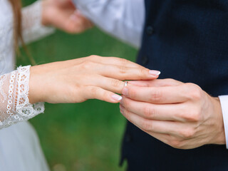 The groom puts the bride's wedding ring on her finger.