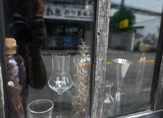 windows display with vintage glasses, vase of caspia flowers and bottles