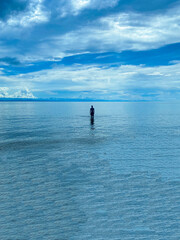 silhouette of a person standing on the water in the middle of the sea