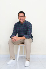 Asian man sitting in a bench while smiling to the camera