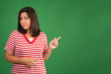 Plump woman indicates with fore finger at blank copy space for your promotional text on green background