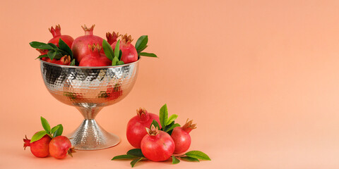 Pomegranates in a silver bowl on a coral background, Rosh Hashanah (Jewish New Year holiday)...