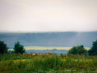 Morning fog over the fields in the valley. A plain under gentle hills. Dawn landscape.