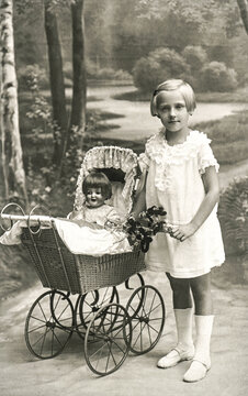 Old photo of little girl with doll toy. Vintage picture