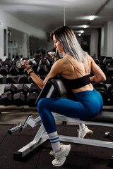 Sporty fitness girl doing exercises using a dumbbells in the gym