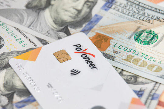 Gomel, Belarus - August 27, 2022: payoneer card with money in the background. Transfer and payment using mastercard.