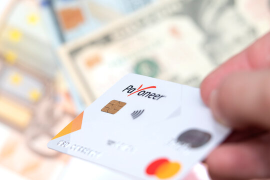 Gomel, Belarus - August 27, 2022: payoneer card with money in the background. Transfer and payment using mastercard.