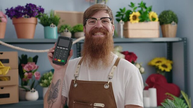 Young redhead man florist smiling confident holding data phone at flower shop
