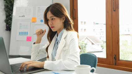 Successful business concept, Businesswoman holds pen and researching data on laptop for new project