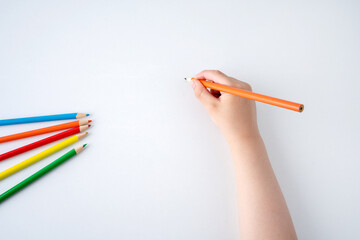High angle shot of child hand draws a orange pencil - Powered by Adobe