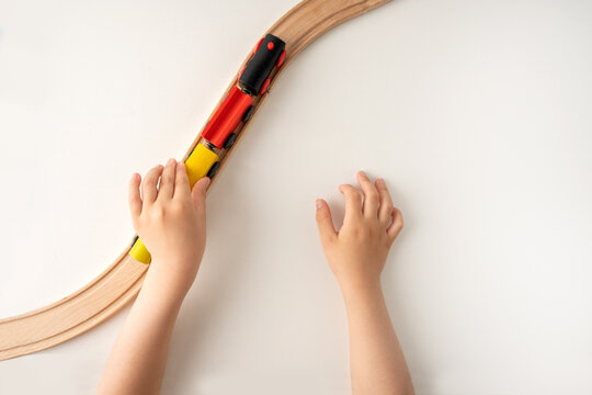 High Angle Shot Of A Kids Hands Playing With Wooden Toy Train On White Background With Blank Space For Text With Top View.