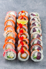 set of different colorful maki sushi rolls with tuna, salmon, shrimp, crab and avocado on a dark gray background