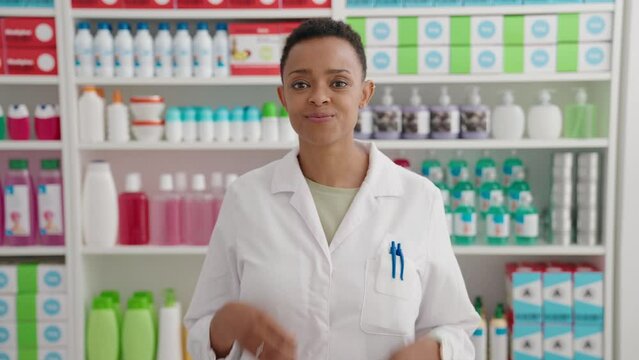African american woman pharmacist smiling confident doing ok gesture with thumbs up at pharmacy