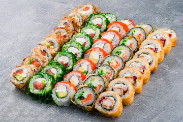 set of different colorful maki sushi rolls with tuna, salmon, shrimp, crab and avocado on a dark gray background