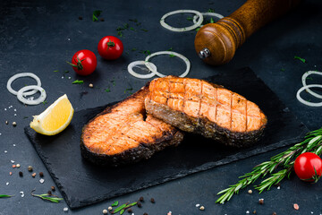 Grilled salmon fish on black stone background