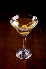 close-up on martini cocktail glass with olive. James Bond 007's Vesper and wooden table seen from above