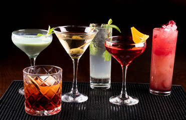 Collection of professionally prepared cocktails on rubber stand on front pub counter