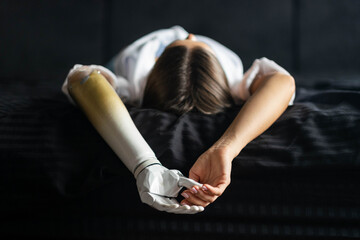 Close up two hands of woman with bionic arm on black bed at home, person lost her arm, girl...