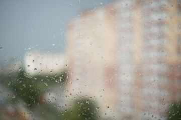Raindrops on the window. A blurred silhouette of a multi-story building outside the window