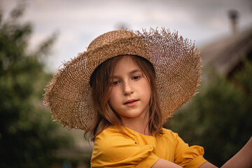 cute little girl in a yellow dress and straw hat walking through the woods