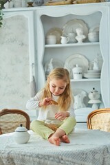 Obraz premium A preschool girl holds a cookie jar in a vintage dining room. Retro interior.