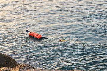 diver swimming by the harbour rocks in the sea in the light of dawn