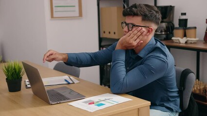 Young hispanic man business worker using laptop with boring expression at office