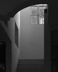 Black nd white photo of interior of modern house with white walls. Light coming from glass window.