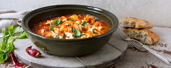 casserole with shrimps in tomato sauce with feta cheese on a light table