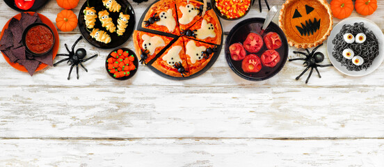 Fun Halloween dinner party top border over a white wood banner background. Above view. Ghost pizza,...